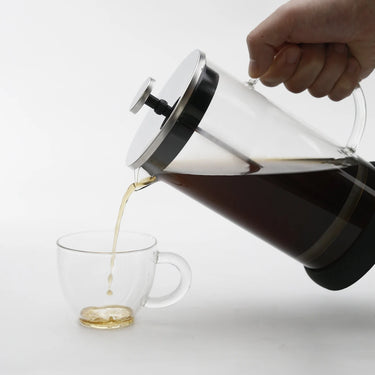 plunger being used pouring coffee into clear glass cup